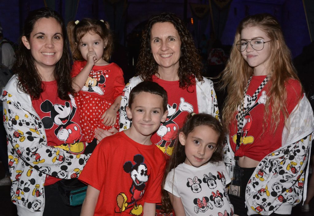 A family dressed in Mickey Mouse shirts and jackets