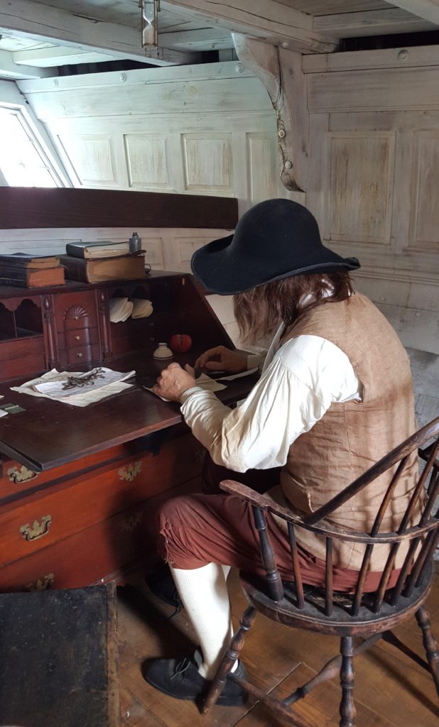 a colonial man sits at a desk